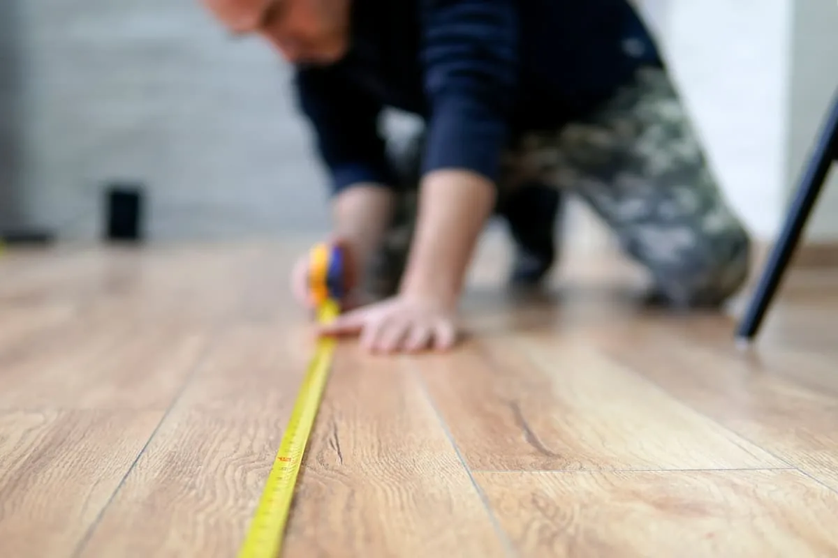 Measuring a floor with a tape measure for a free estimate